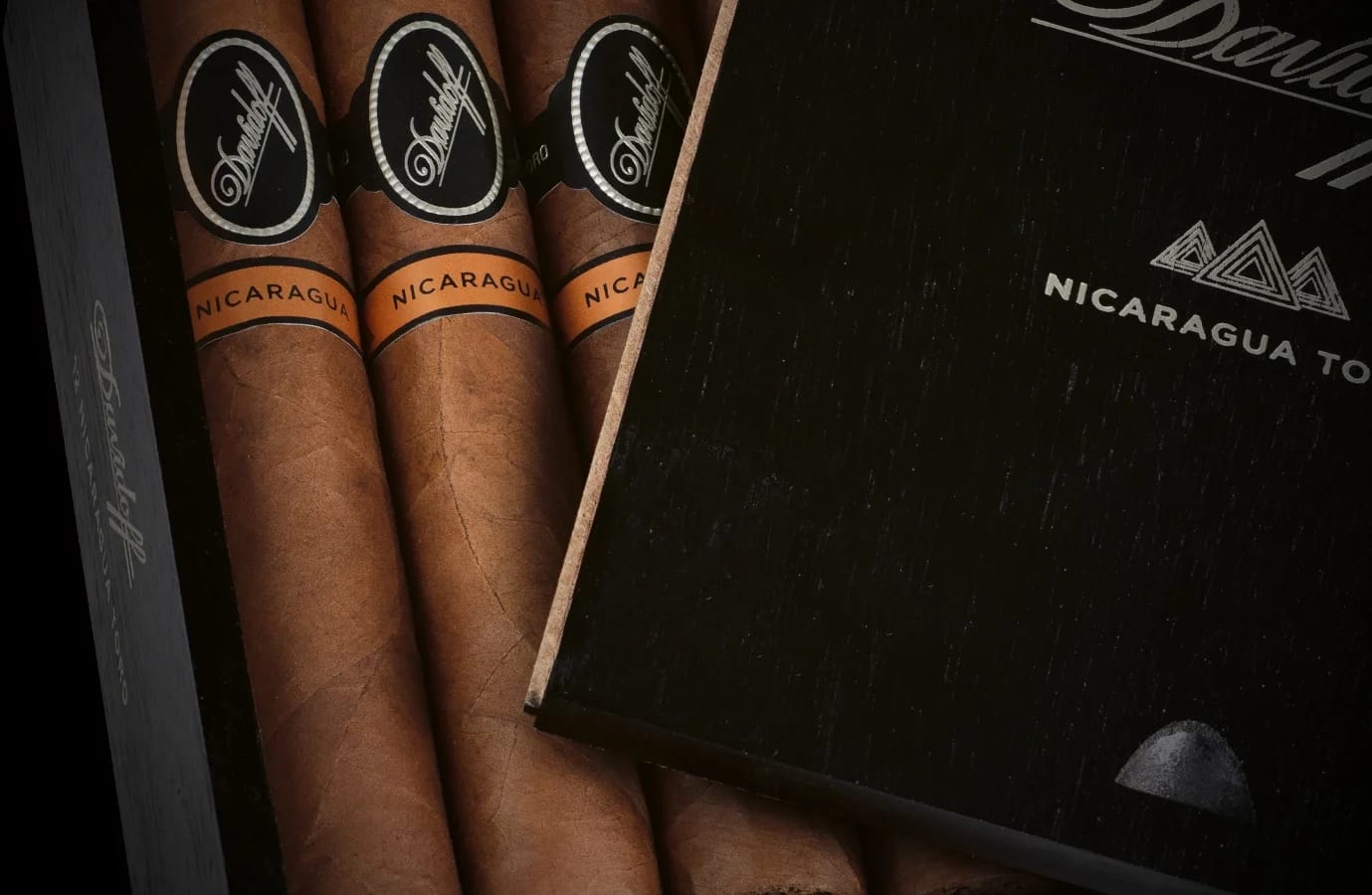 Close-up of Davidoff Nicaragua Toro cigars in a black wooden box, featuring smooth brown wrappers, orange bands, and a premium luxury presentation.