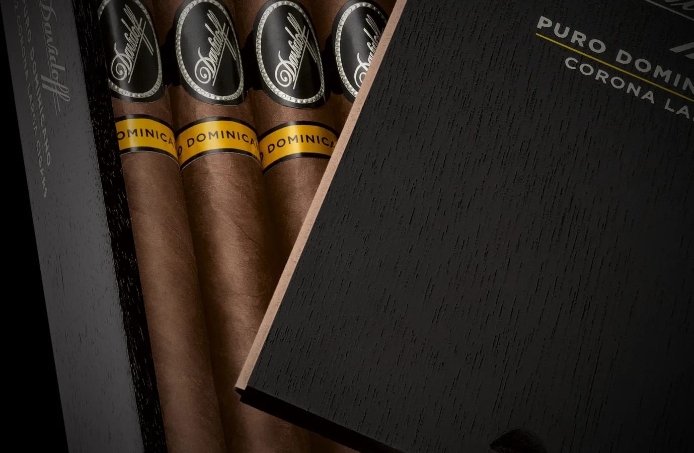 Close-up of Davidoff Puro Dominicano Corona Larga cigars in a black wooden box, with brown wrappers and yellow bands in a refined luxury display.