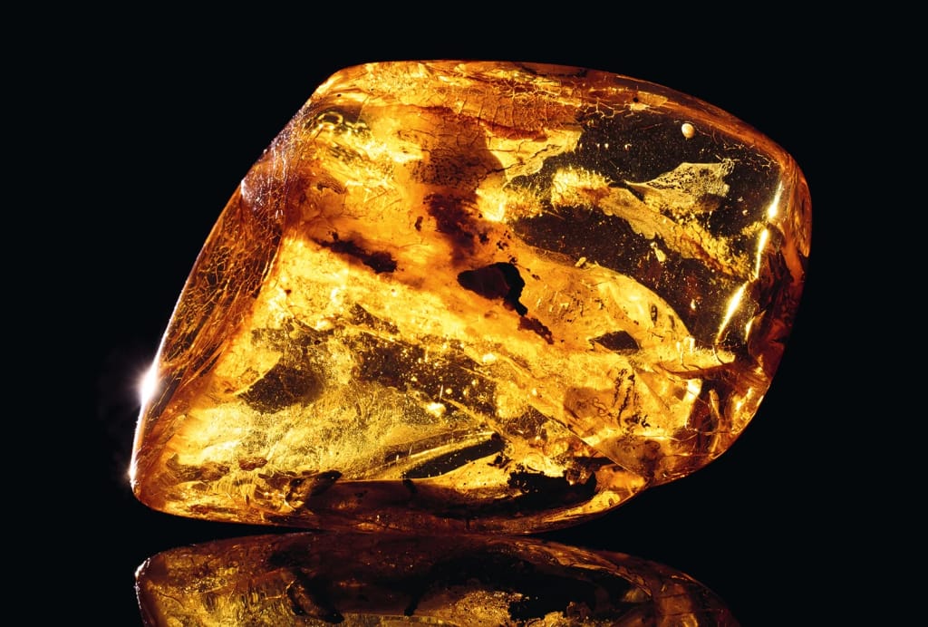 Polished golden amber gemstone with warm hues and natural inclusions on a dark background, glowing with rich, radiant warmth and elegant, luminous depth.