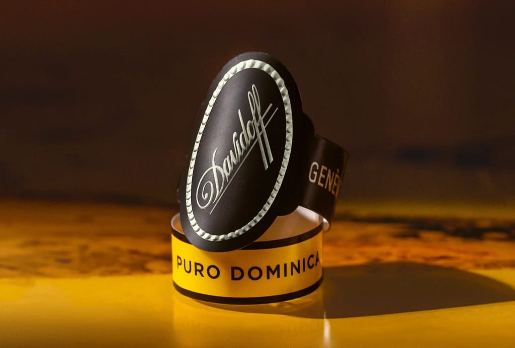 Close-up of a black and gold Davidoff cigar band labeled "Puro Dominicana" on a glossy surface, with warm lighting creating a refined, sophisticated ambiance.